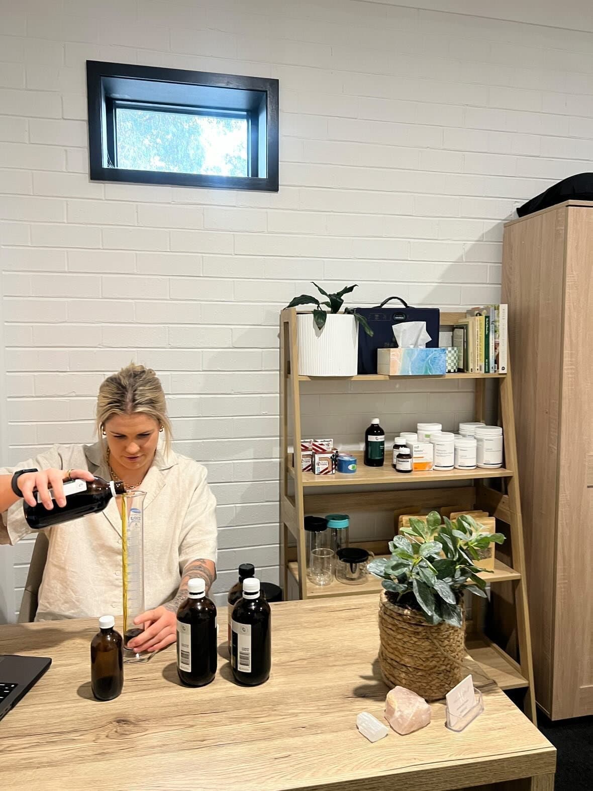 Alanna measuring a herbal tincture at the dispensary bench.