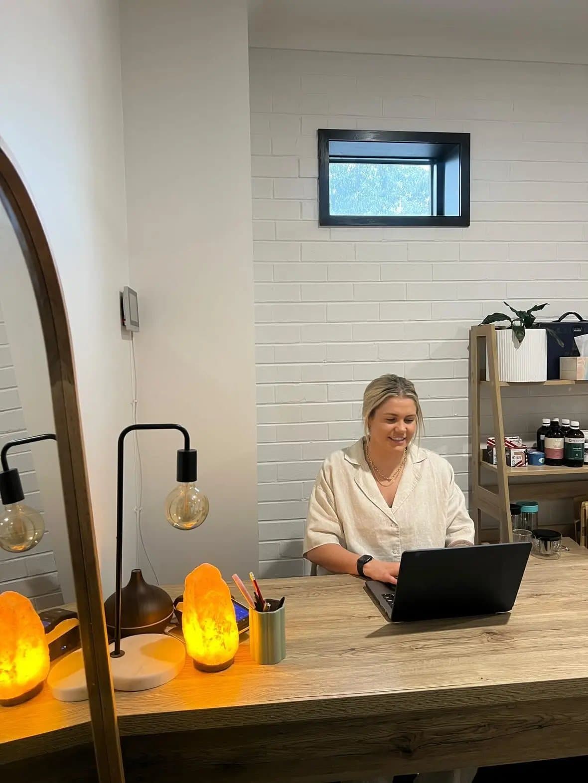 The consulting room — a warm desk lamp, salt lamp and plants beside the practitioner's chair.