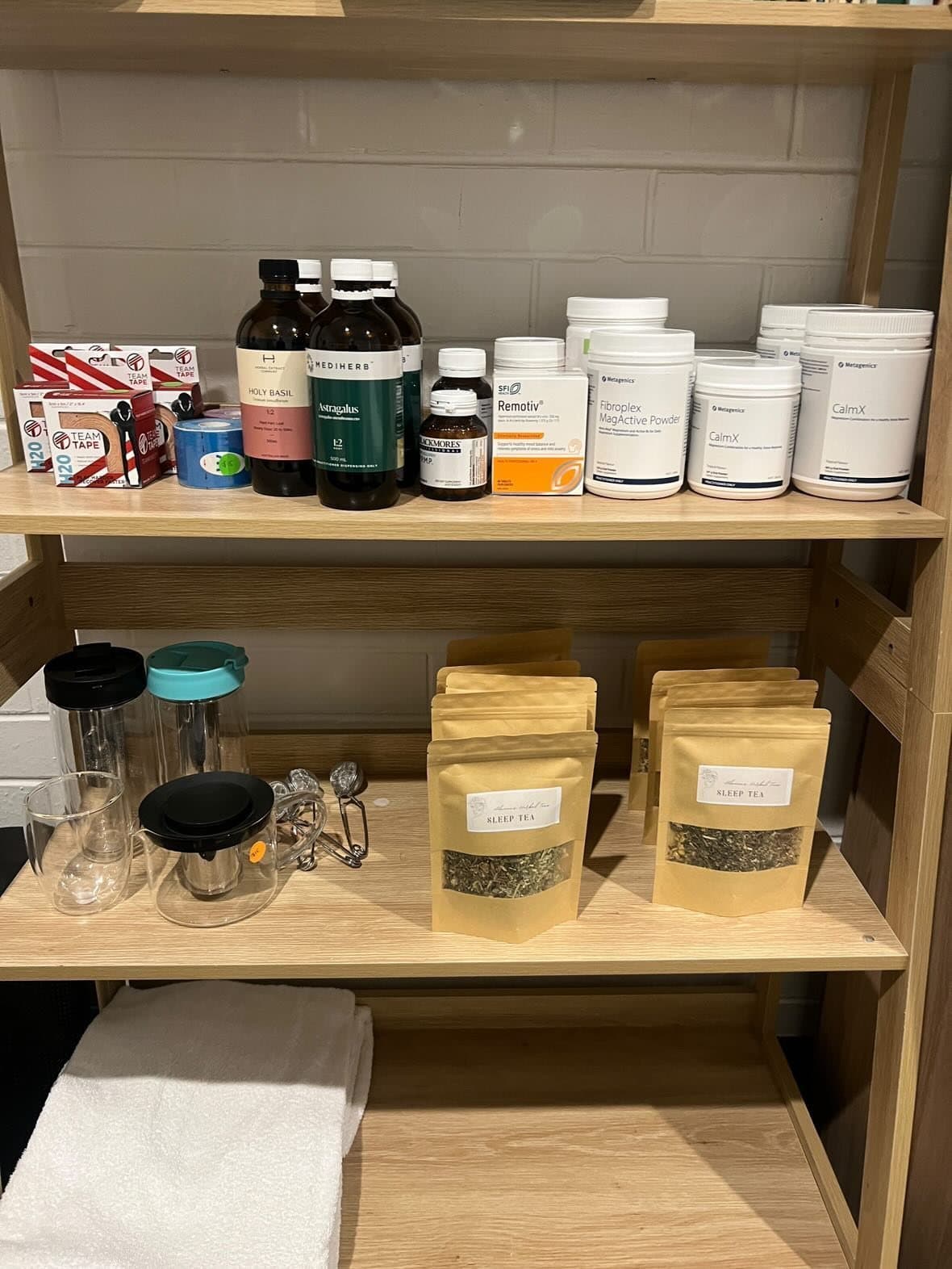 The clinic's herbal dispensary — practitioner-only powders, tinctures and supplements on open shelving.